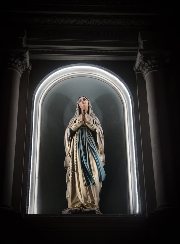 A beautifully illuminated Virgin Mary statue within a church setting.